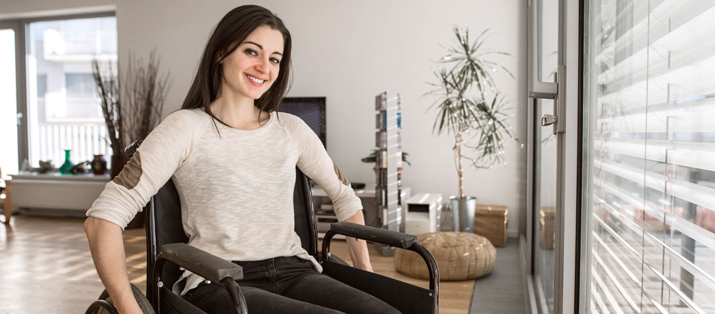 Young woman in a wheelchair smiles in her modern living room