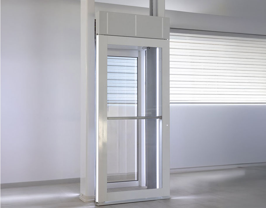 Side view of the LUMA Homelift with the door open, highlighting the glass panels and minimal footprint in a bright room