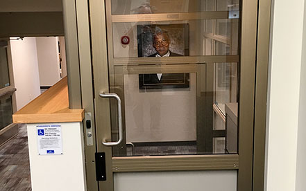 Genesis shaftway model vertical platform lift for wheelchairs with a photo of man in the hallway