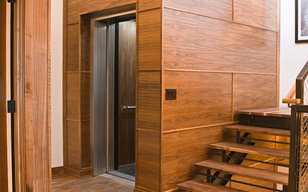 Home Elevator with open doors in a dark hardwood hallway