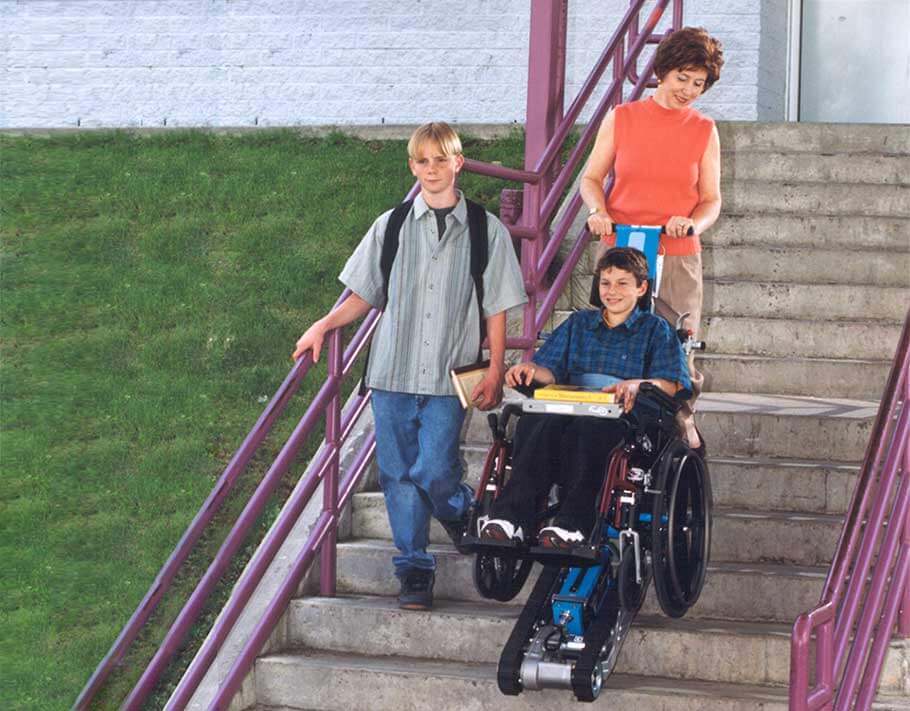 Teacher using a Stair-Trac to help a wheelchair bound student down the stairs alongside another young studen