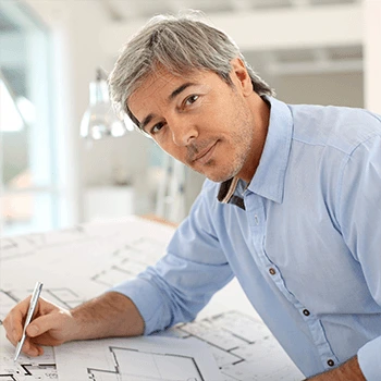 Middle aged man working on his floorplans looks at camera