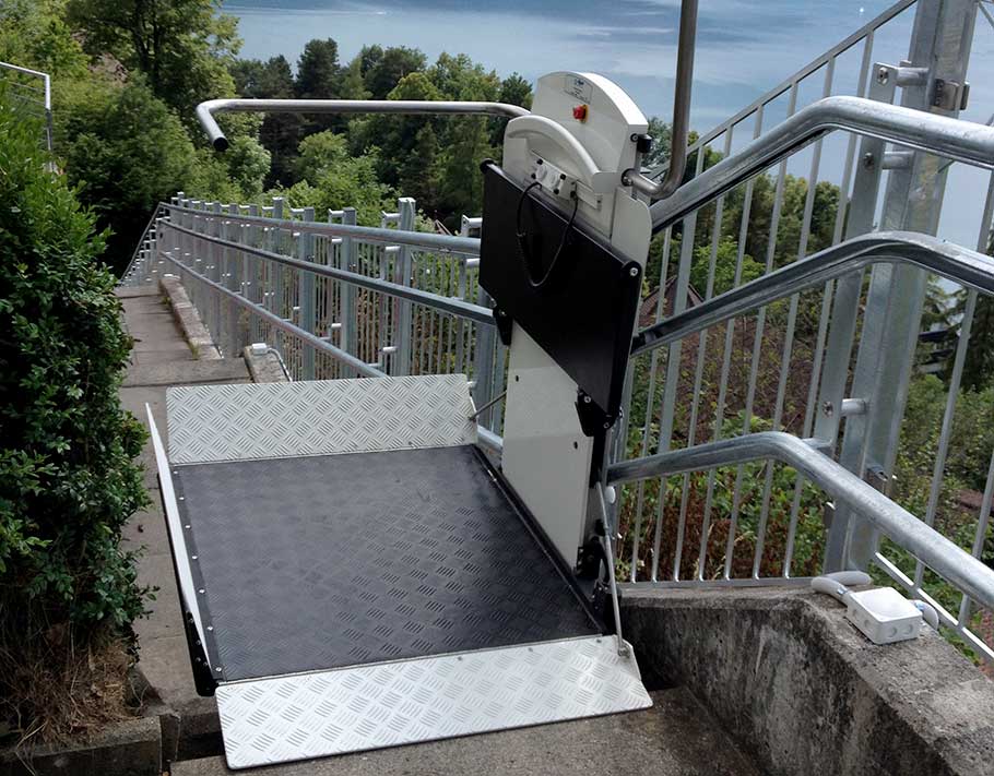 Treppenlift ARTIRA von Garaventa Lift im Aussenbereich an der oberen Haltestelle einer langen Treppe